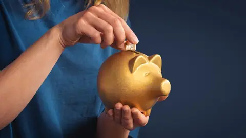 Kobieta z pieniędzmi i złotą skarbonką na niebieskim tle