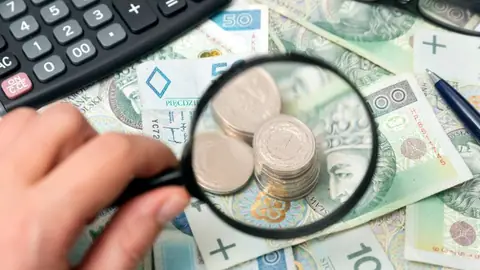 Lupa z pieniędzmi i kalkulatorem na stole